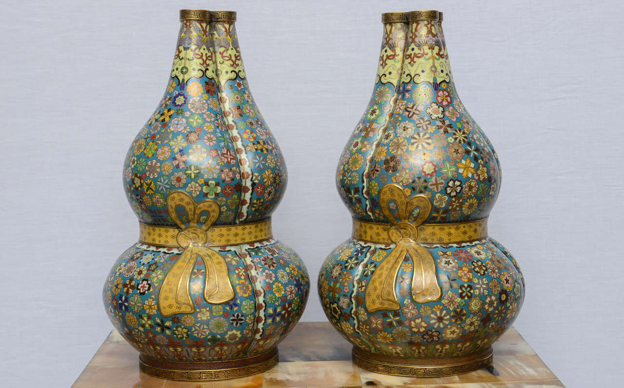 Each vase is finely decorated with a mill-fleur (thousand flowers) design
on a blue ground.
The shape of the vases is a composition of three double gourds joined
by a yellow ribbon, an extremely auspicious symbol.