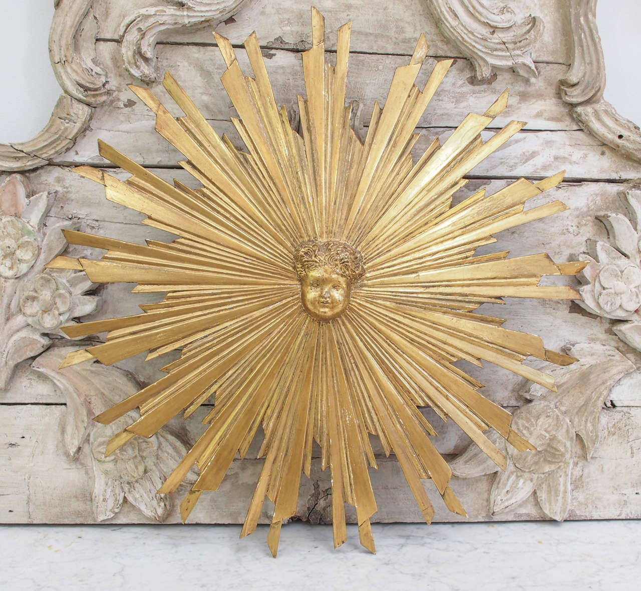 French carved and giltwood starburst with putti head, 19th century all wood.