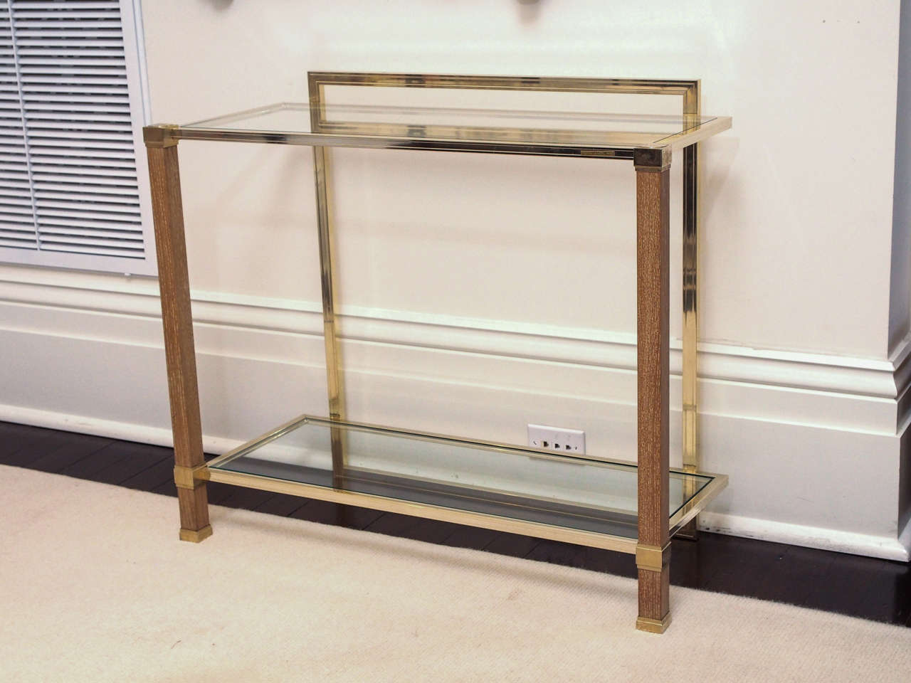 Rectangular console in brass-plated metal and oak cerus. Inset glass shelves. Signed Pierre Vandel, Paris.