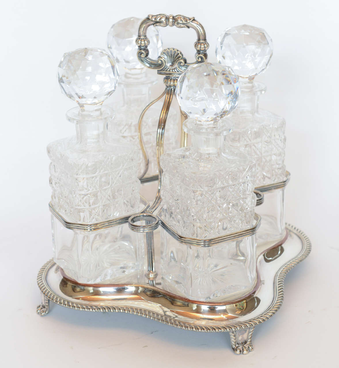 Striking silver plate footed tantalus with four crystal decanters.