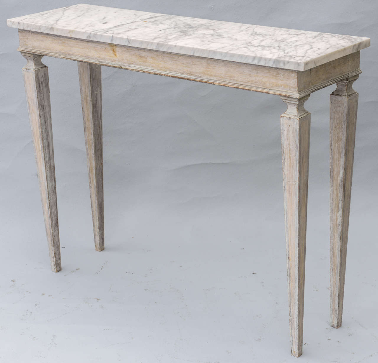 Pair of narrow console tables, having distressed, painted finish, white veined marble top, raised on tapering square legs.