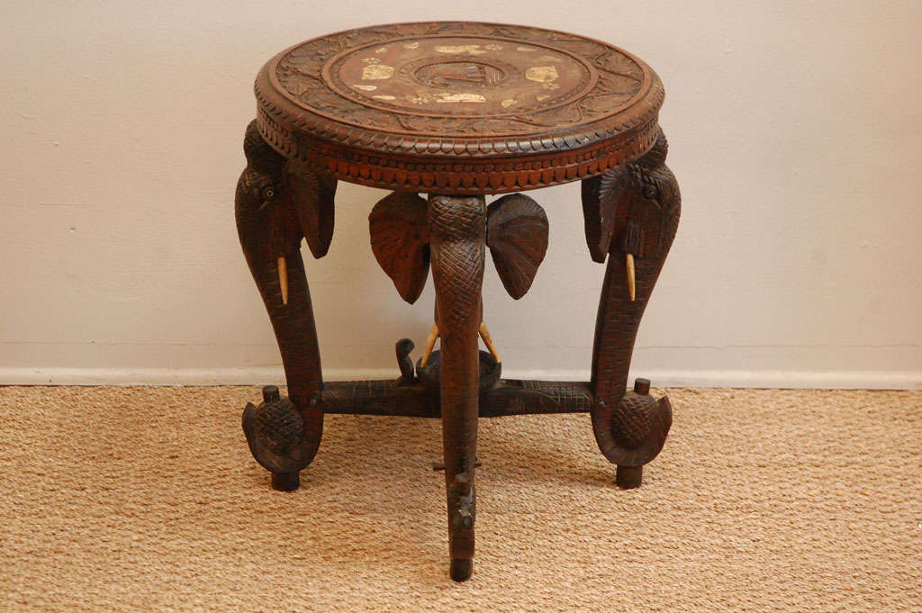 Exotic carved wood side table with bone inlay top and carved elephant-head legs.