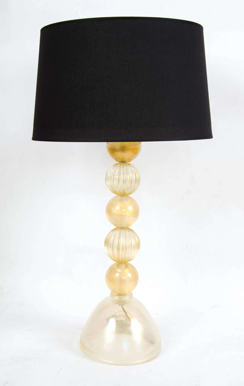 1950s Italian lamps of hand-blown gold fleck Murano glass spheres, alternating between smooth and fluted finishes mounted on a circular base. Black shades optional.