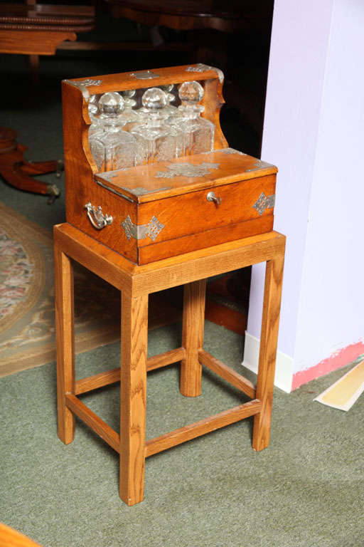An English Antique Oak Tantalus with Secret Drawer, fitted with original decanters.
