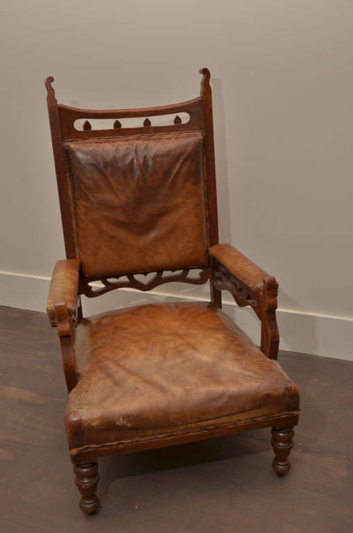 Pair of Gothic-Style Brown Leather and Oak Armchairs, England, circa 19th Century. 

These handsome and dramatic armchairs consist of sturdy oak frames, fantastic hand-carved details, and original brown leather that shows a rare wear and patina. The