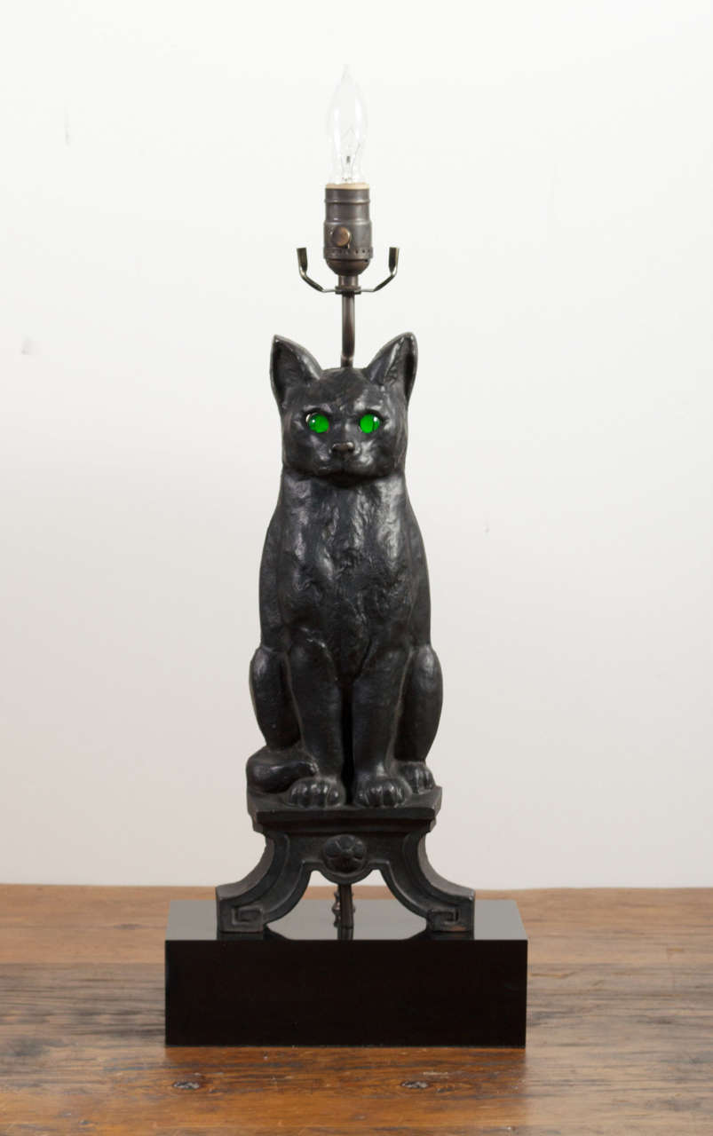 Pair of Black cast iron cats with bright green eyes, mounted on black lacquered wood.