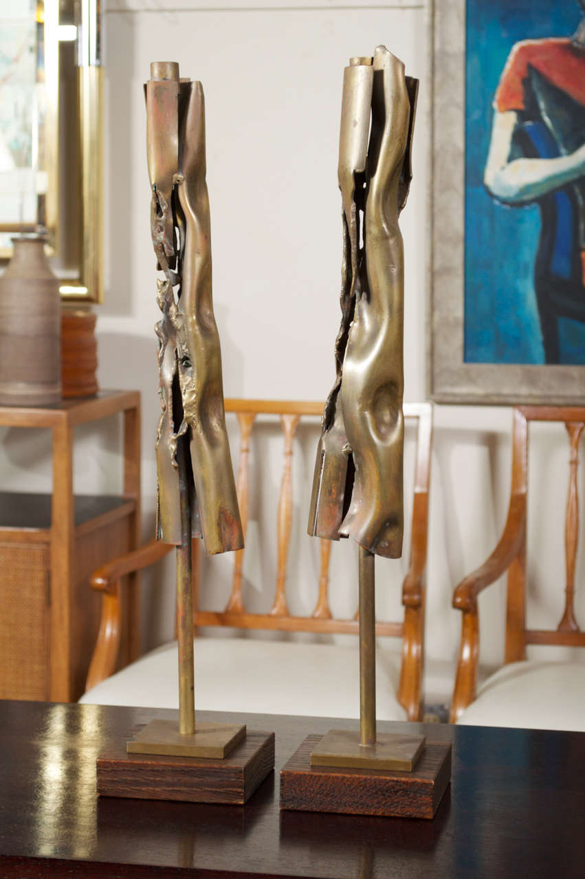 A pair of1973 brutalist candle holders in Bronze, on wood block bases.  Both are signed R Stanton. The Bronze has been cut, smashed, scrunch and in spots heated until it was starting to melt, out of that came their wonderful unique brutalist form.