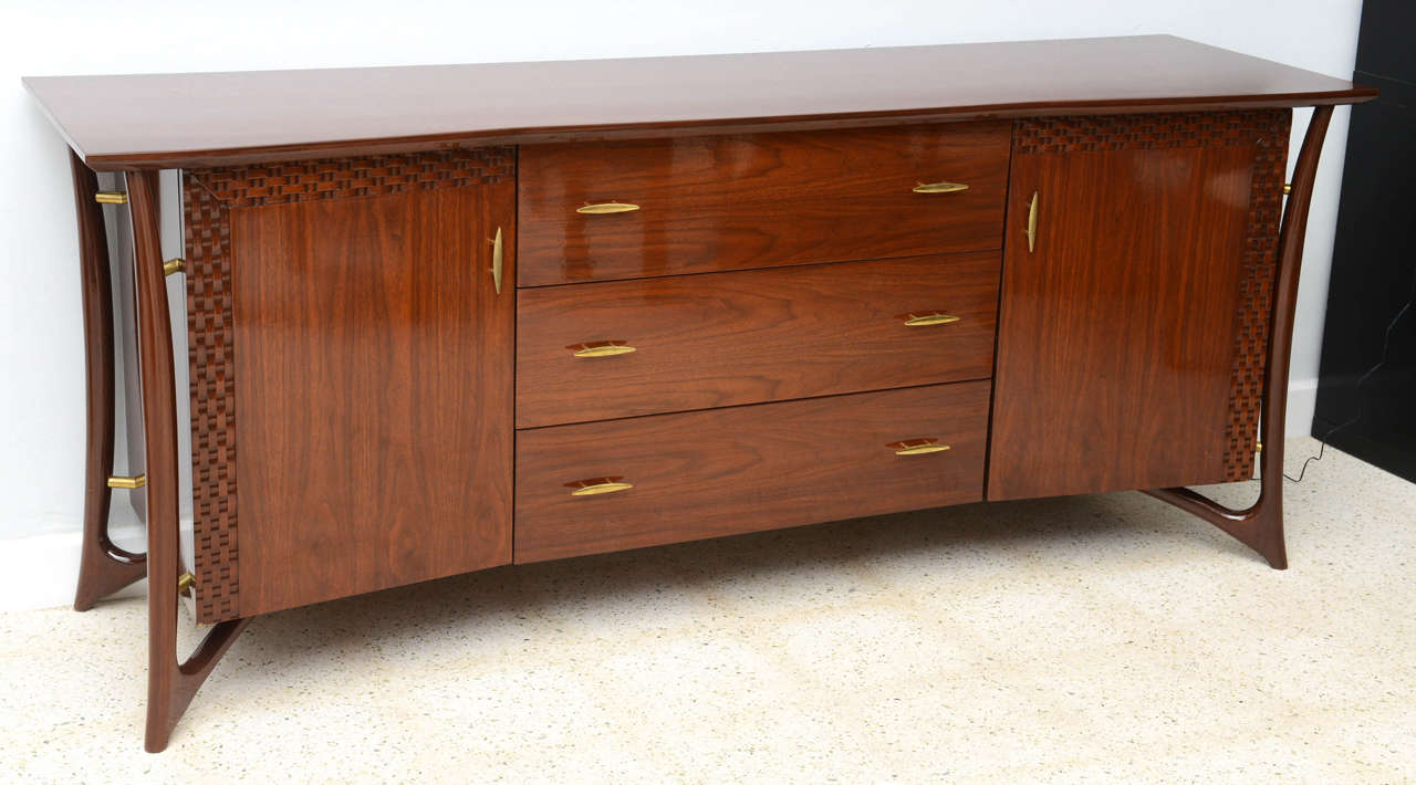 The rectangular top above three central drawers flanked by two cabinet doors with woven wood detail, all flanked by structural pierced legs.
Marked make in Denmark to rear.