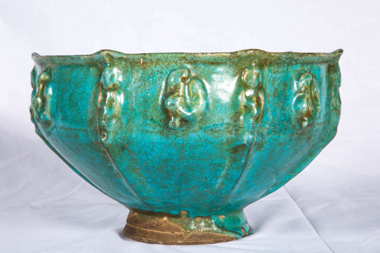Very impressive and rare example of a medieval Islamic pottery. Stone paste body covered with a turquoise-blue glaze with moulded applications of human figures and mythological birds on a short foot. The size is unusual for this type of