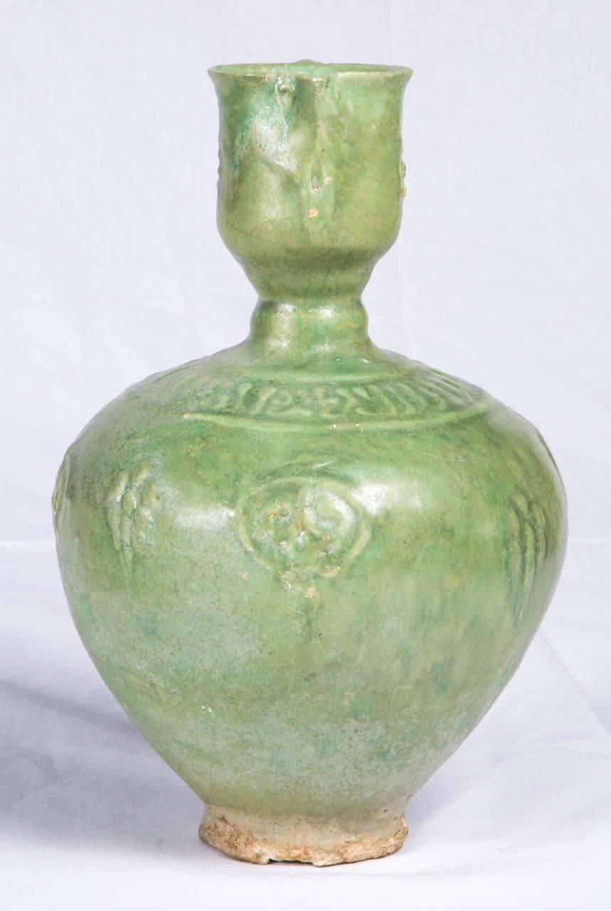 Fine and rare early Islamic ewer with cylindrical body and moulded calligraphy on the upper part covered with a rare green monochrome glaze in the manner of celadon. Iranian have tried to create a glaze that imitated its characteristic gray-green