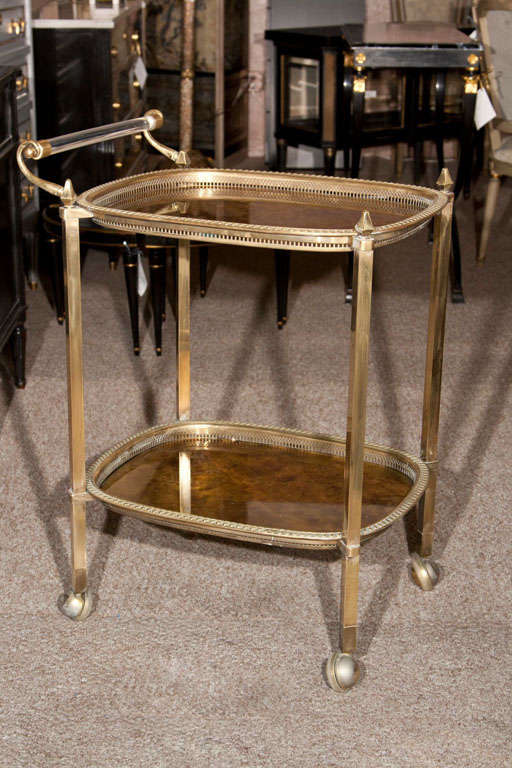 An ultra chic brass bar cart, two-tier each with gilt-glass removable tray, joint by brass legs and lucite handle.