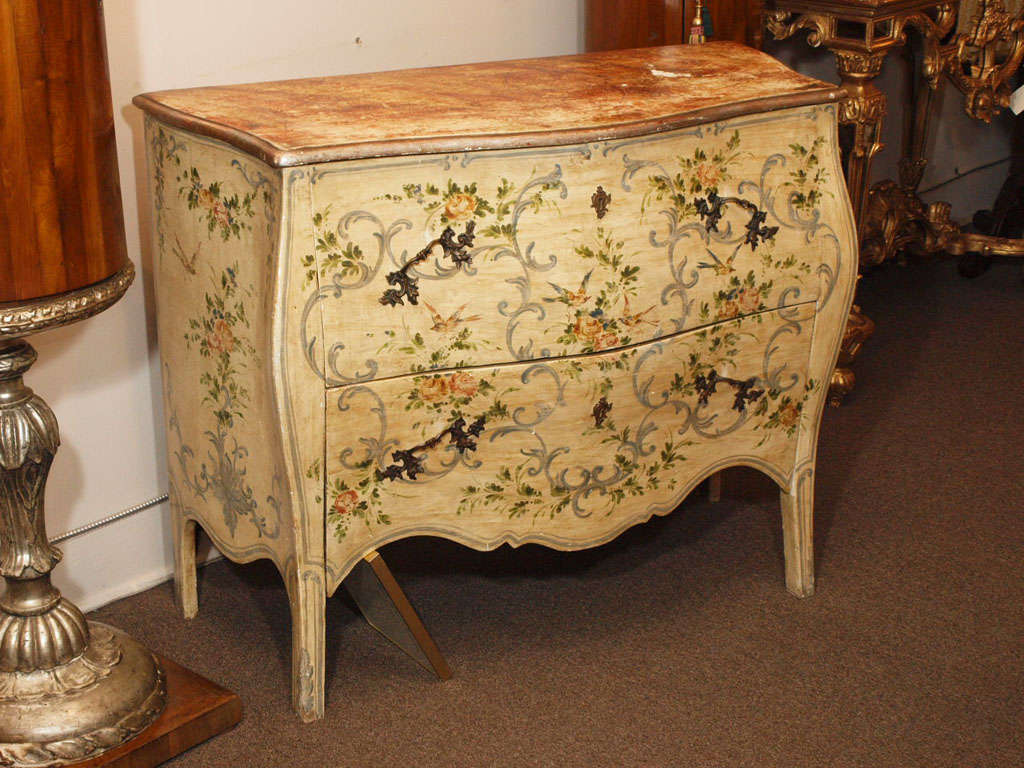A hand painted Venetian Style bombe', circa 1970's. Faux marble top. Two handpainted large drawers in scroll and floral motif with pewter finish rococo hardware.