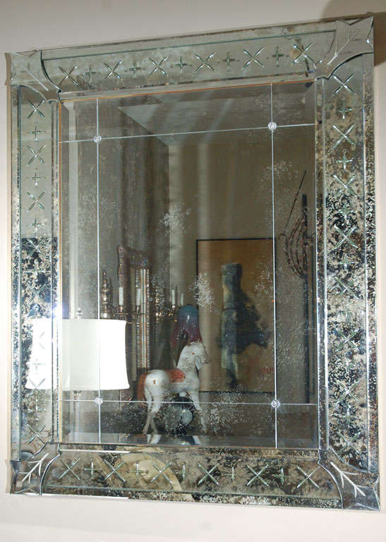 Impressively scaled mirror with an etched, bevelled and heavily antiqued mirrored frame and lightly antiqued field mirror. Mirrors are mounted on a 22-karat yellow gold gilded frame. Field mirror is dived into nine segments with glass