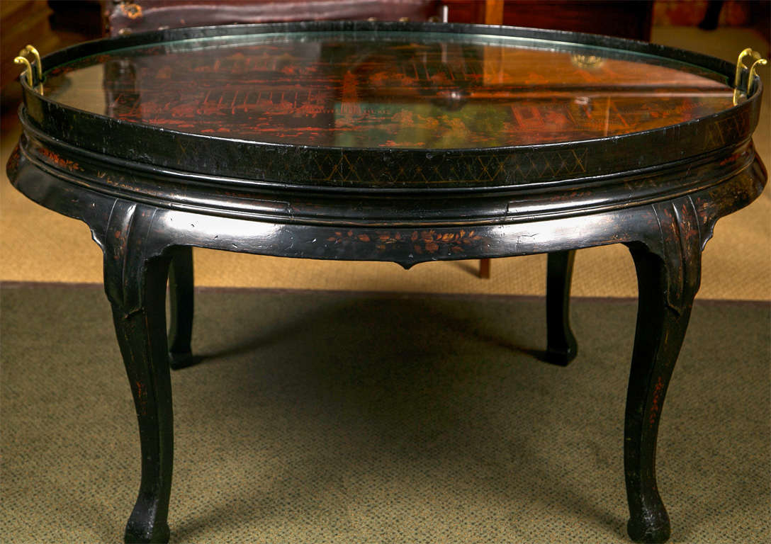 An oval CHinese lacquer tray mounted on a later stand. The tray depicts daily life in 19th century China with figures of musicians and river vendors.