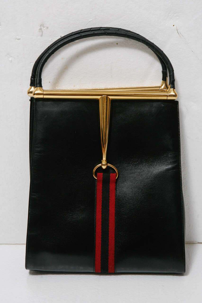 Vintage 70's Gucci handbag in black leather, goldtone hardware and classic Gucci ribbon accent.  Metal handle is wrapped in leather band.  Excellent condition. Handle drop is additional 
3 1/2