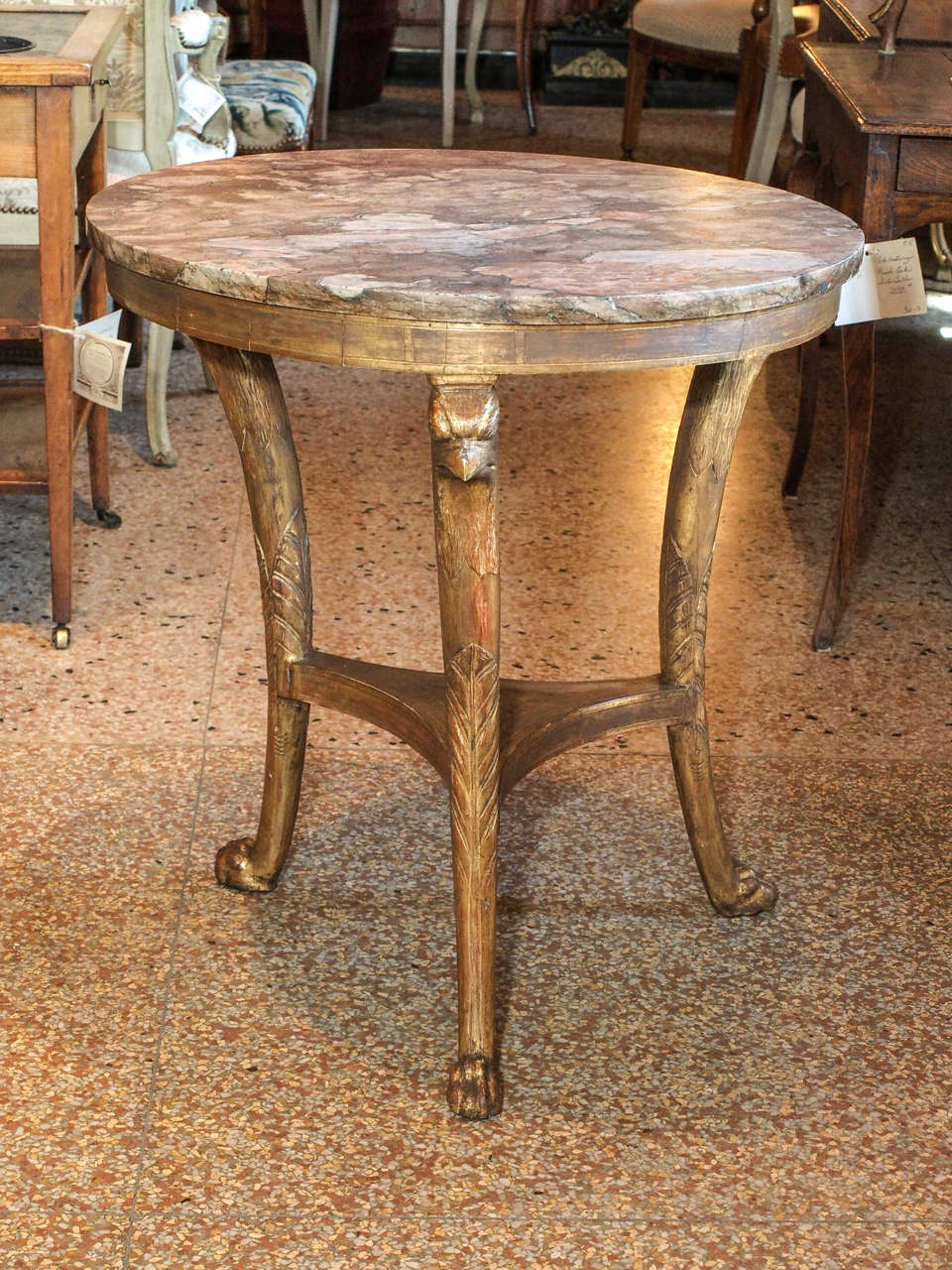 A 19th century Italian gueridon.  A Brescia marble top supported by 3 griffin glazed gilt legs joined by a shelf ending in paw feet.