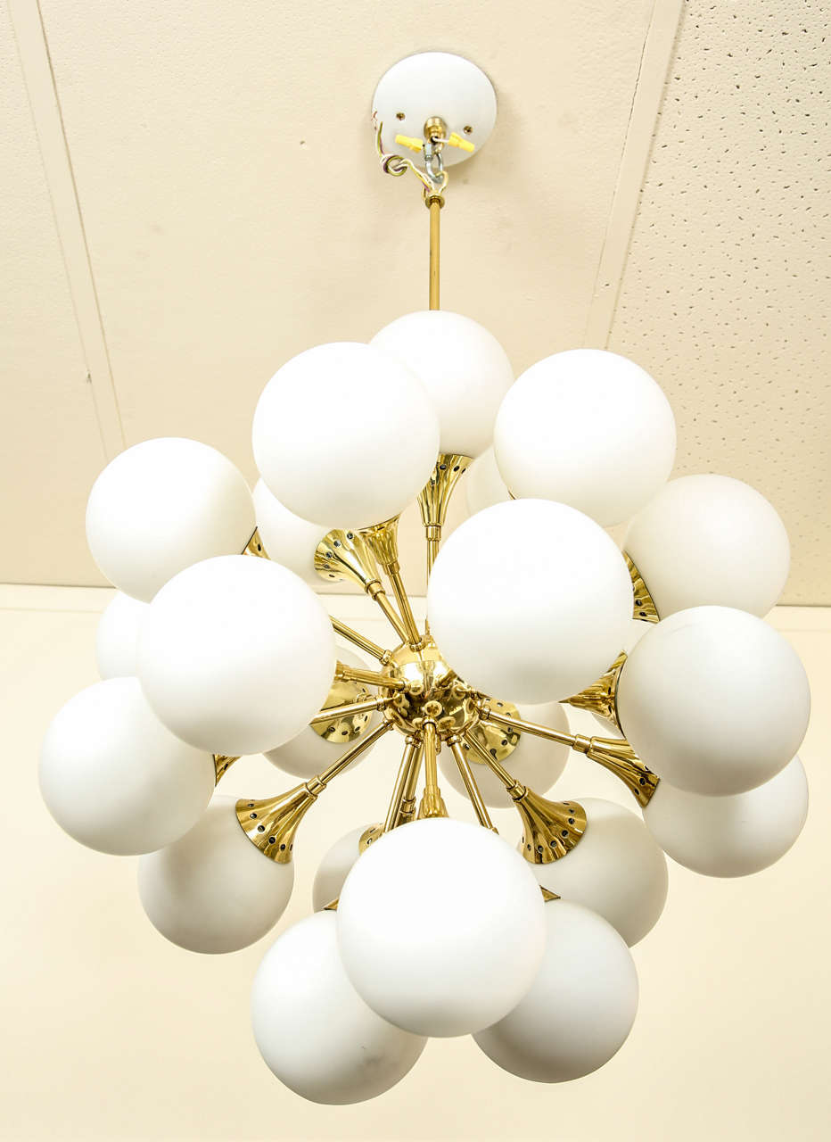 Fabulous brass sputnik chandelier.  The fittings are trumpet shaped, and the bulbs are concealed under frosted glass globes.
There are 21 light sources and globes.