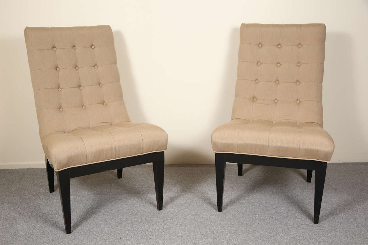 Elegant pair of Camel colored fabric upholstered biscuit tufted slipper chairs by James Mont. The chairs are mounted on black bases.