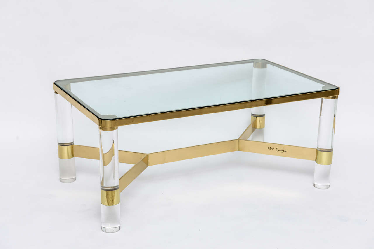 Exceptional quality and craftsmanship have gone into this signed Karl Springer polished bronze coffee table with acrylic legs and glass top.