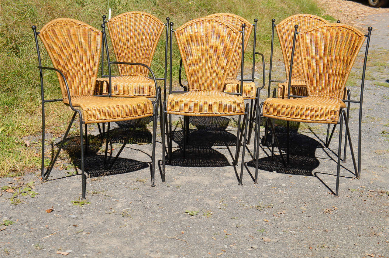 A set of six chairs with solid, round iron framing, and woven rattan seats and backs. Solid, sturdy, and very comfortable design, with a playful, simple line. Two armchairs, and four side chairs.