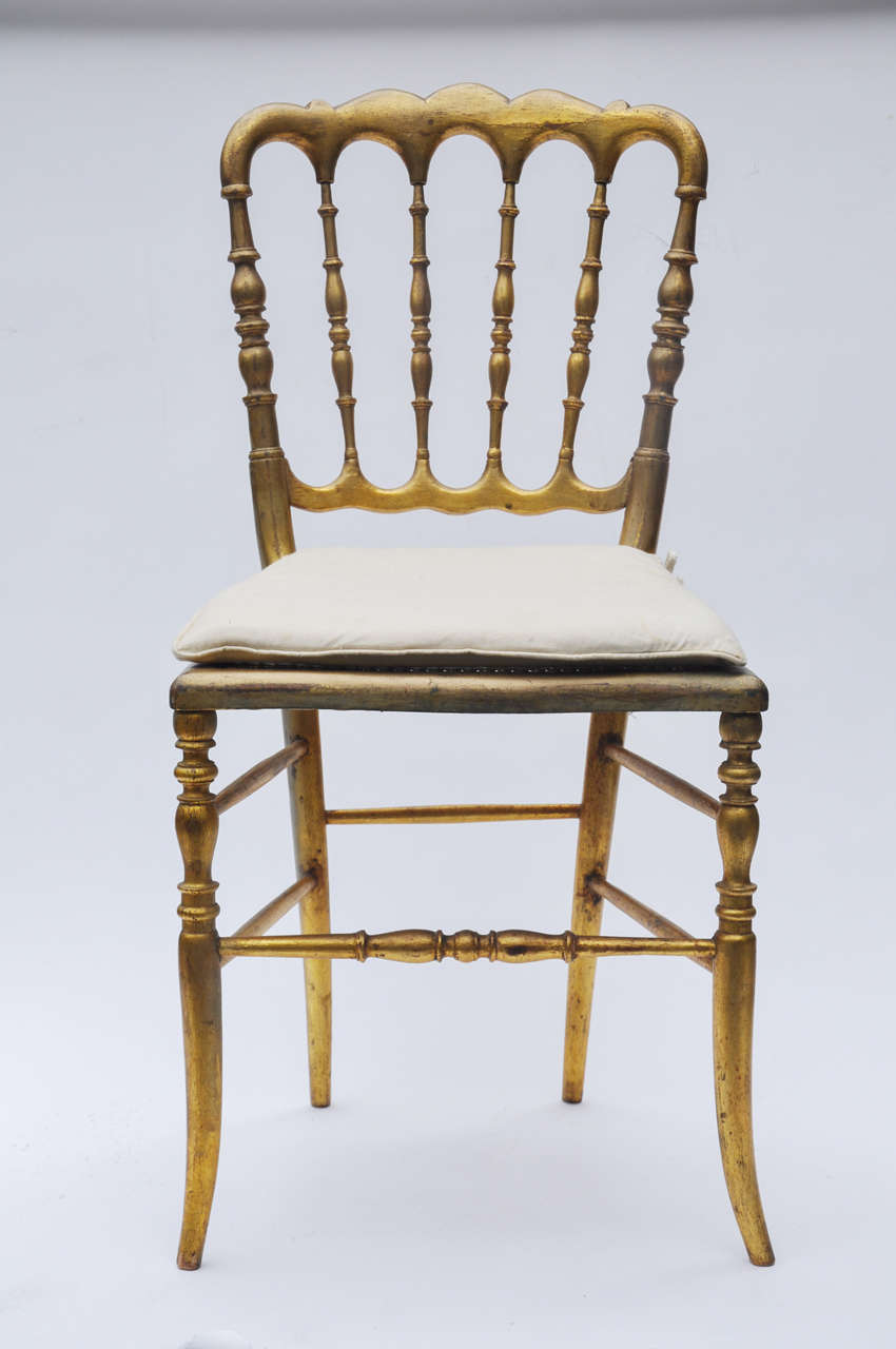 Seven Gilded Ballroom Chairs with Stylish Shaped Backs and Fine Turned Spindles Throughout. Gilt Finished Beech Wood, Cane Seats with Tie Down Muslin Pads, France, Circa 1890