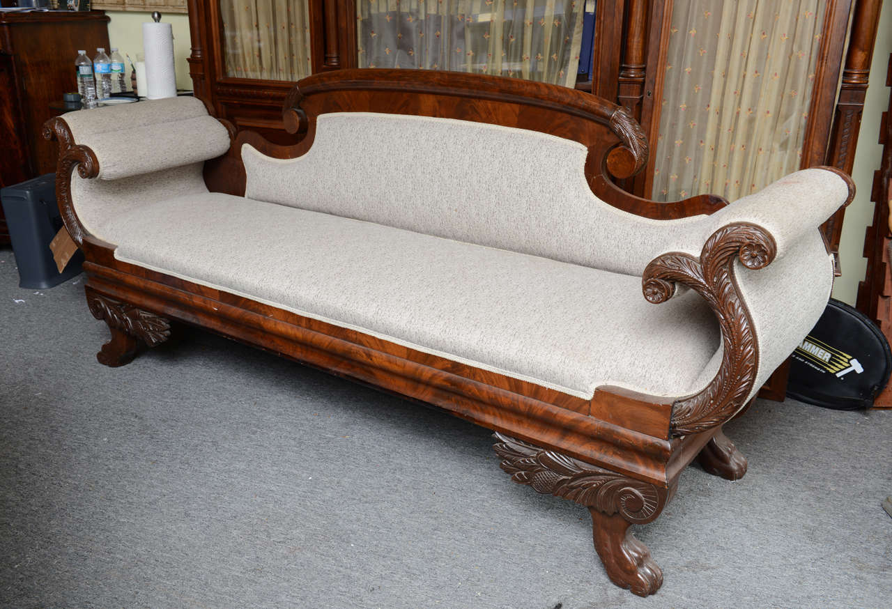 This is a superb quality mahogany settee. Its sits on lion carved feet, to either side of the settee it has carved scrolls and the back is flamed mahogany. This is the original finish and has been recently recovered