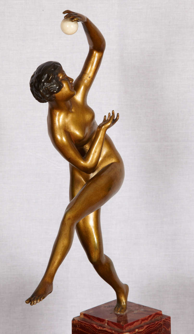 Beautiful dancer holding an ivory ball in brass sculpture with a gilded patina signed by  Guiraud- Rivière (1881-1947). Mounted on a red onyx base. Good condition. Normal wear consistent with age and use.