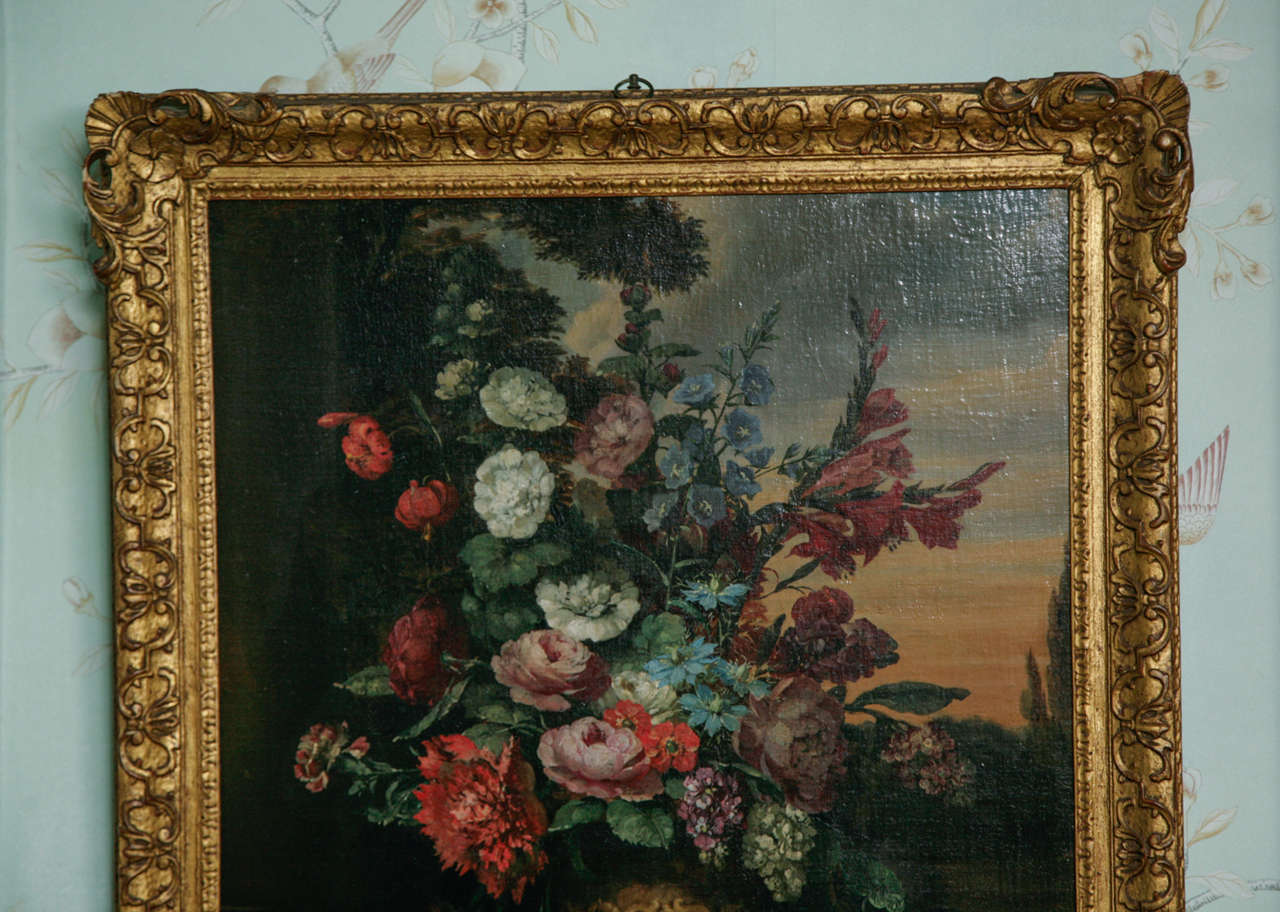Continental School, 18th century still life Dutch School. Oil on canvas. Still life with a classical vase of flowers on a stone plinth beside a column, a landscape beyond, unsigned and in a gilt and carved wood swept frame. A good quality,