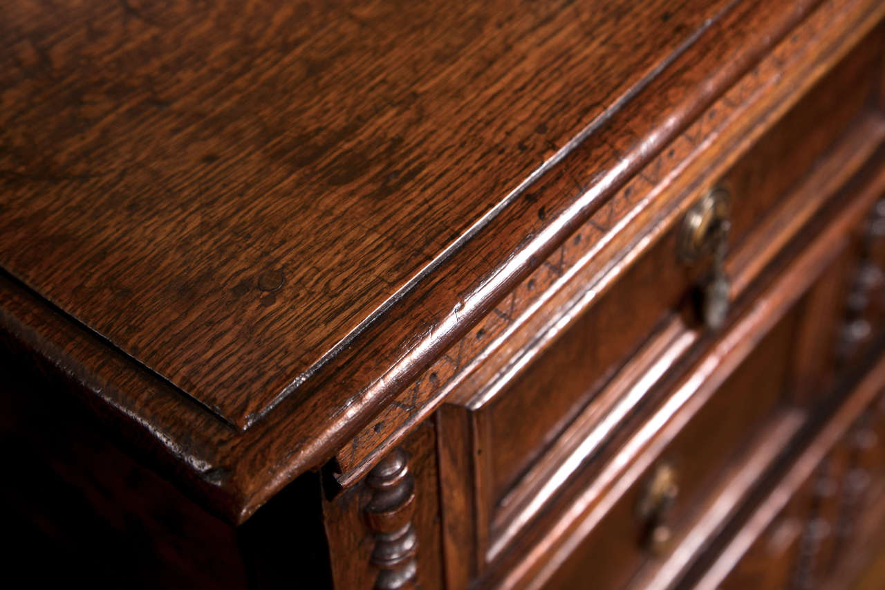Three magnificently paneled drawers define the front of this three-drawer chest in quarter sawn and straight grain oak. Each drawer panel is flanked by split balusters and the chest is supported on bun feet. Double panel sides further add to the