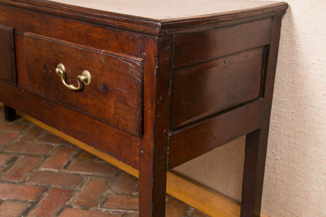 “Unassuming” is probably the best word to describe this low oak dresser base/server. With a deep apron and narrow drawers, this straight-legged server was most likely sitting behind a sofa, but could possibly have been a serving table in a cottage.