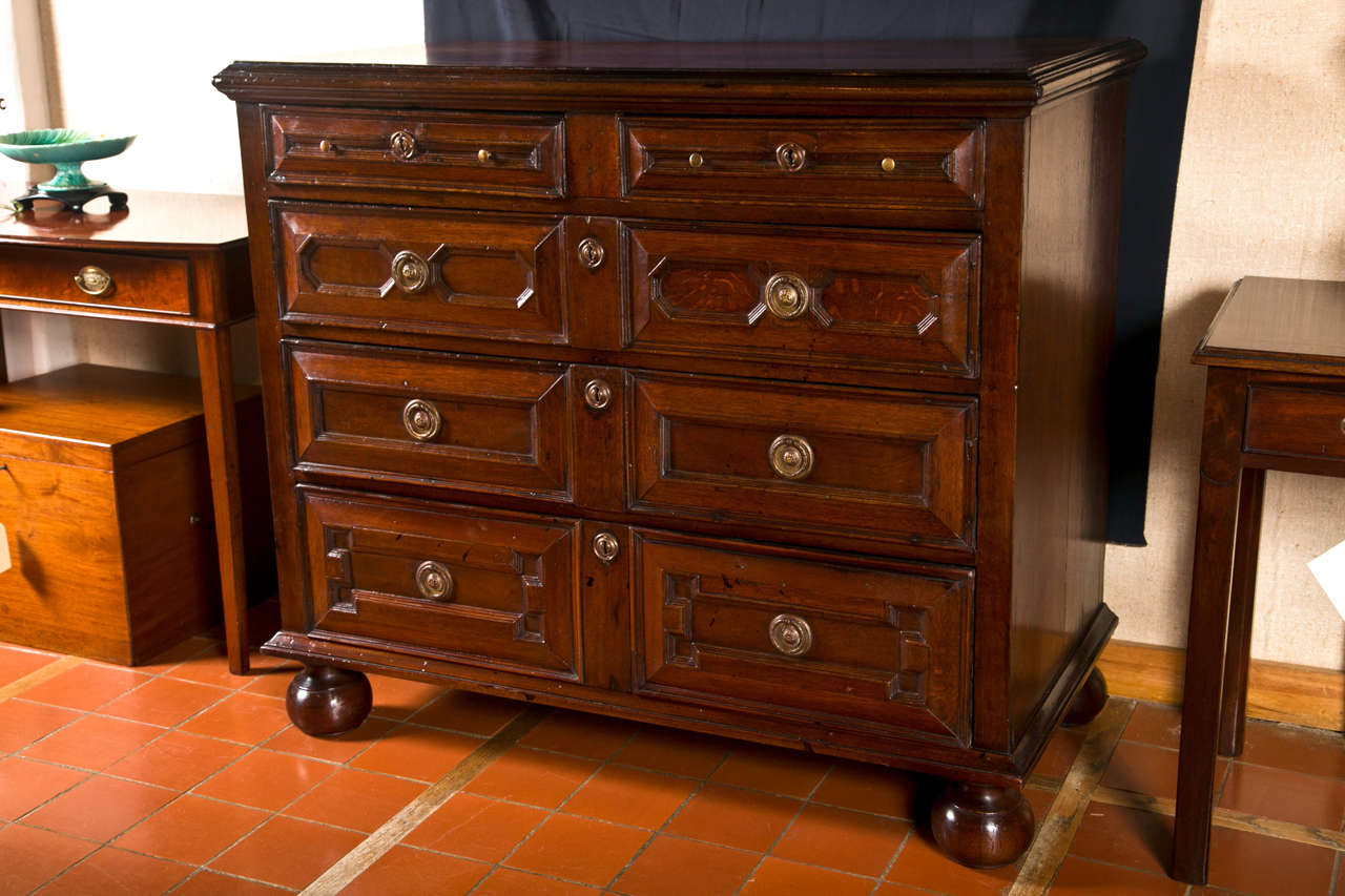 This large oak chest has four graduated drawers with unique panels for each drawer. Technically not a period Jacobean piece, it still faithfully hews the line with its sturdy construction, geometric paneling and bun feet. Its substantial size offers