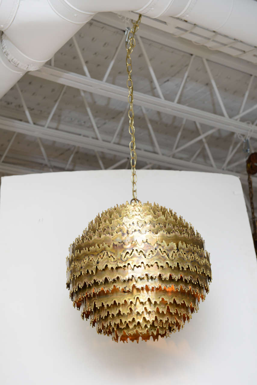 One of our favorite chandeliers, this stunning Brutalist orb by T.A. Greene for Feldman Lighting is formed from concentric layers of torch-cut brass rings. Magical and glowing as the light escapes through each successive ring.