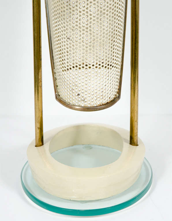 A mid-century modern umbrella stand comprising a lacquered and perforated metal shell within a brass tube frame supported on a lacquered cast iron and slab glass base. After Fontana Arte. Italian, circa 1950.