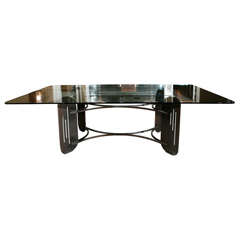 Large glass-topped dining table with abstract metal base