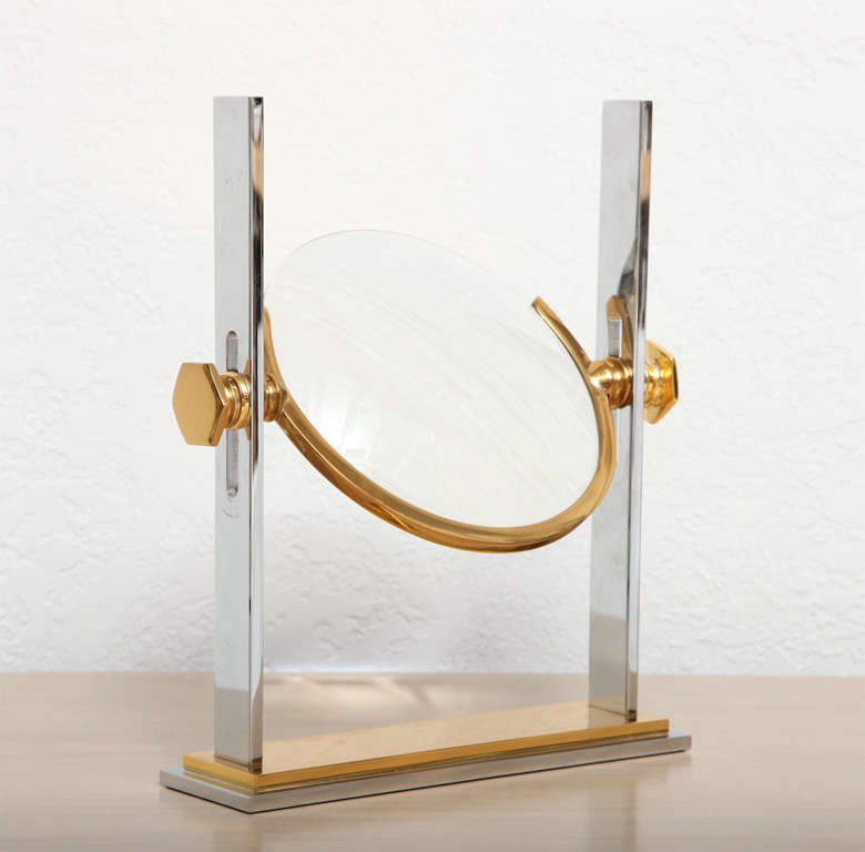Live life larger with this wonderful chrome and brass magnifying glass and stand by Karl Springer. A witty, Mini-Me version of his vanity mirror, we have to warn you that objects viewed under this glass may appear not only larger - but more