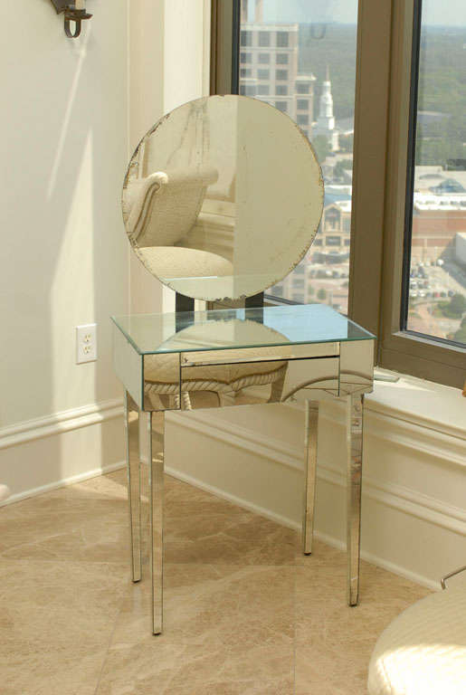 Fabulous Art Deco round vanity mirror mounted onto a mirrored table with one drawer and square tapered mirrored legs.