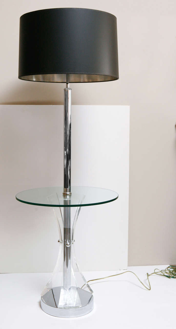 Sleek mid-century floor lamp with table top. Chrome base with flared and bowed Lucite pieces that create the base supporting a clear glass top.    
Top overall height is 56