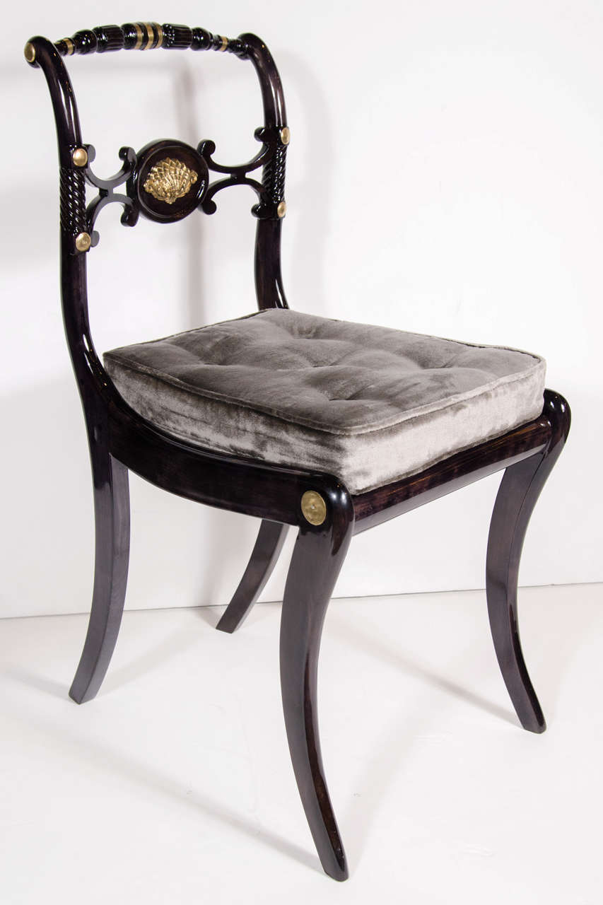 This stunning chair was crafted from ebonized walnut. It features a saber leg design and gilt accents, and hand carved detailing throughout. Newly reupholstered in a luxe pewter velvet. Mint restored condition.
