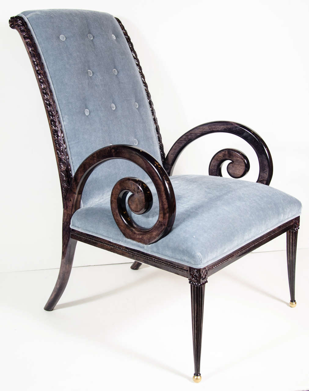 This stunning chair features a spiral arm design and hand carved stylized plume detailing all in ebonized walnut with gilt tips on the feet. It also features button back detailing and has been newly upholstered in a Grey Blue mohair. Restored to