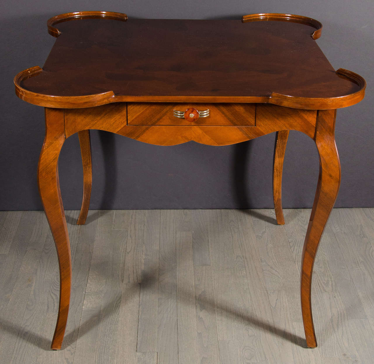 This elegant classic Art Deco game table was realized in France, circa 1925. Handmade in exotic burled walnut, it features rectangular cabriolet style legs; an apron with undulating curves on its bottom; and a drawer with its original streamlined