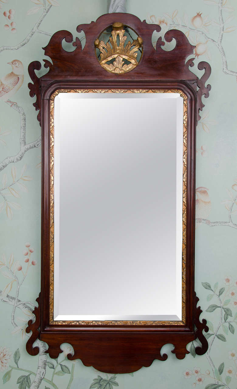 A large late 18th century Georgian mahogany Chippendale design mirror. The frame is made from mahogany veneered onto pine and has a Rococo shaped fretwork detail to the top and bottom edges. The central carving at the top of the mirror is a Prince