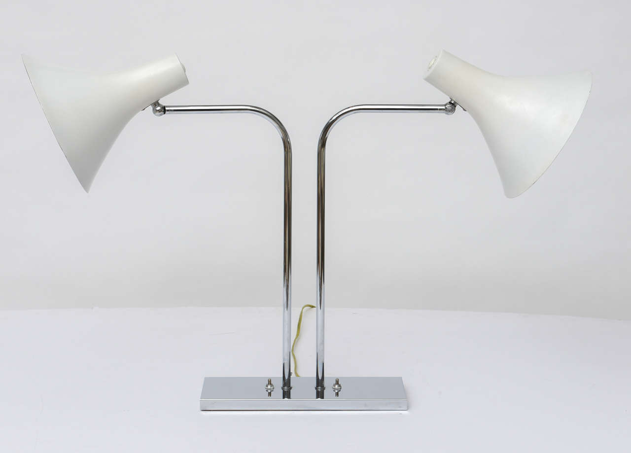 1960's polished chrome double desk lamp by Nessen Studios has swinging arms and lacquered aluminum cone shades that pivot and turn. An elegant and simple classic!