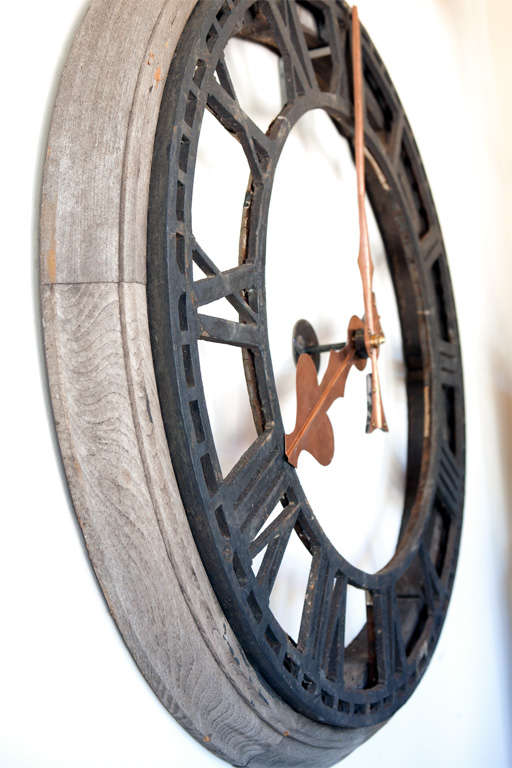 Cast iron clock faces trimmed in original weathered oak. These clock faces have copper hands that have been modified to mount to the wall. They were originally on the four sides of a clock tower in Great Britain.