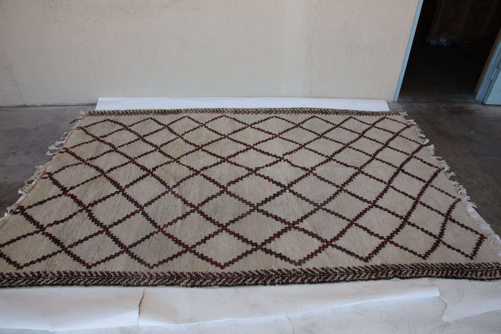 A Moroccan Carpet featuring brown and red arrow designs on an off-white field