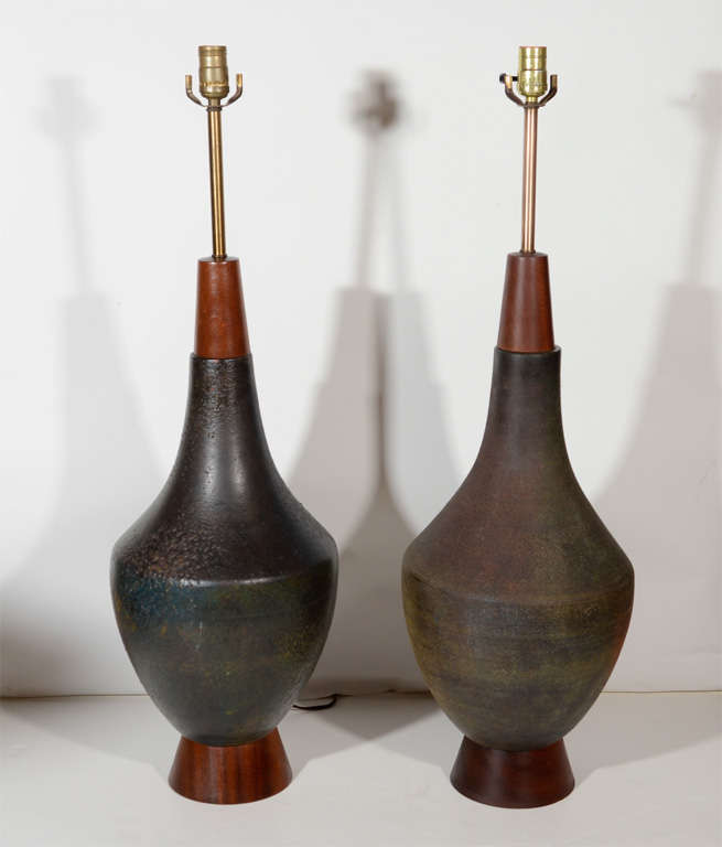 Outstanding pair of modern lamps with stylized urn design.  They are pottery lamps with a Raku ceramic glaze finish, and with teak wood bases and fittings.  The lamps are hand made and have color variations throughout in hues of dark brown, rust,