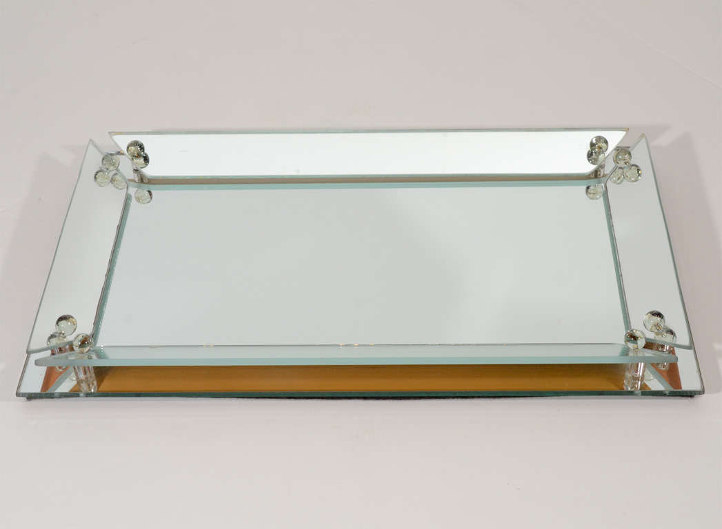 Glamorous bar or vanity mirrored tray with stylized mirrored borders. Raised mirrored borders have modernist slant design and are fitted with glass ball finials, and held by lucite fittings.  A great accessory to a vanity, dresser, or table top.