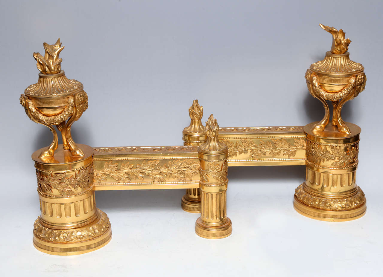 A fine pair of antique French Louis XVI style doré bronze chenets of exquisite workmanship embellished with neoclassical urns adorned with flames representing fire in original doré bronze mercury gilding, 19th century.