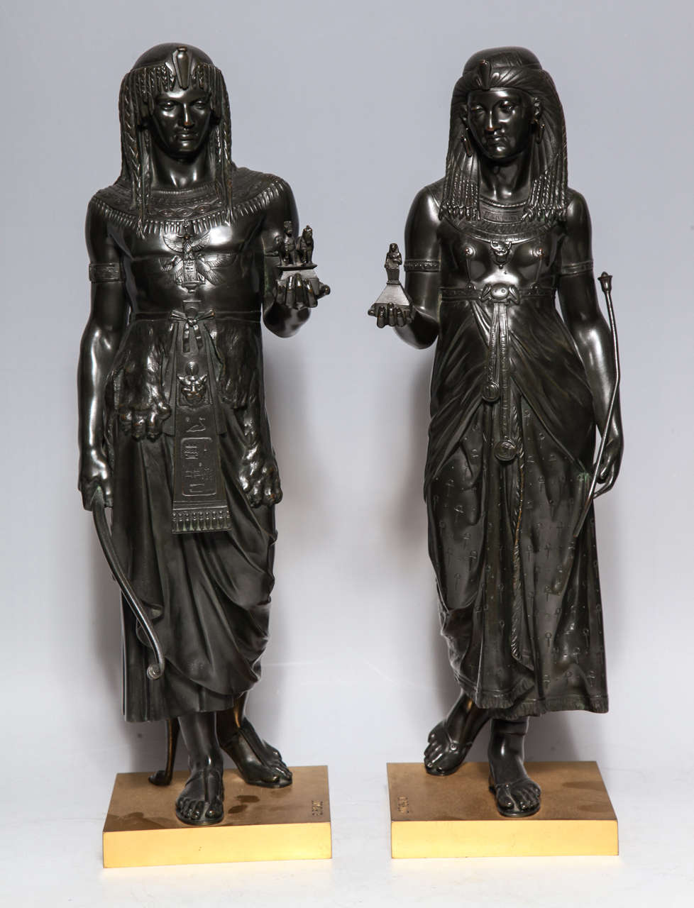 AN IMPORTANT PAIR OF ANTIQUE FRENCH PATINATED BRONZE FIGURES OF ROYAL EGYPTIAN FIGURES PRESENTING GIFTS TO THE PHARAOH ON DORE BRONZE SQUARE FORM PLINTHS By EMILE-LOUIS PICAULT