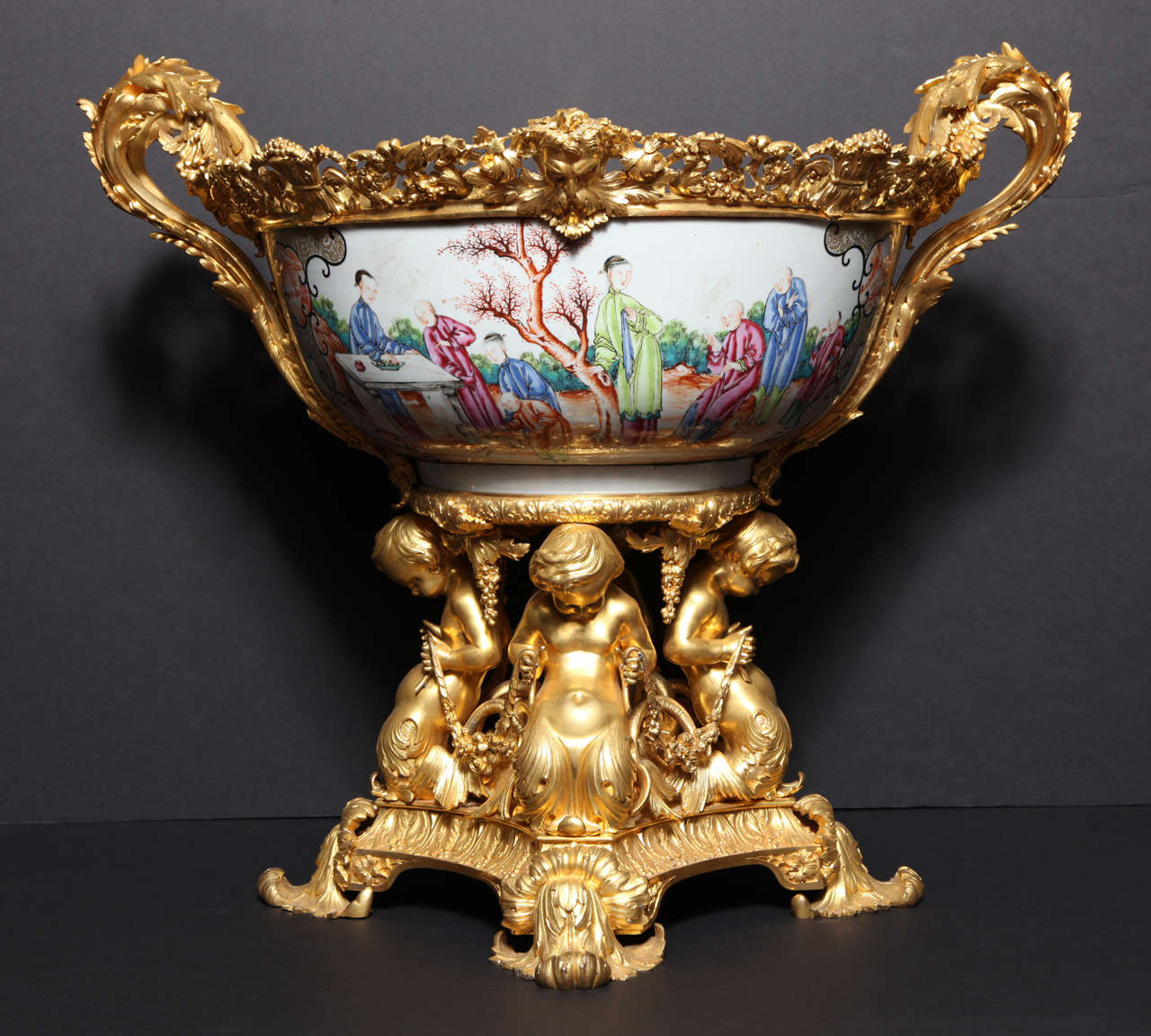 A very large and important Charles X doré bronze and Chinese Export porcelain jardinière, the exterior of the porcelain finely painted with scrolling cartouches of Scholars in a landscape flanked by birds on branches, the interior w ribbon tied