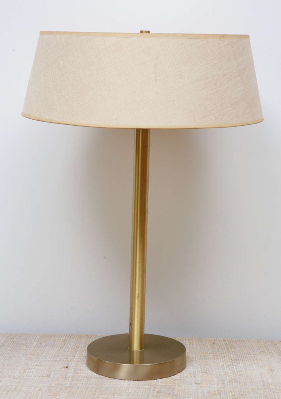 Classic table lamp in polished brass, circa 1950, with original linen shade. The lamp has been recently rewired with a brown silk cord.